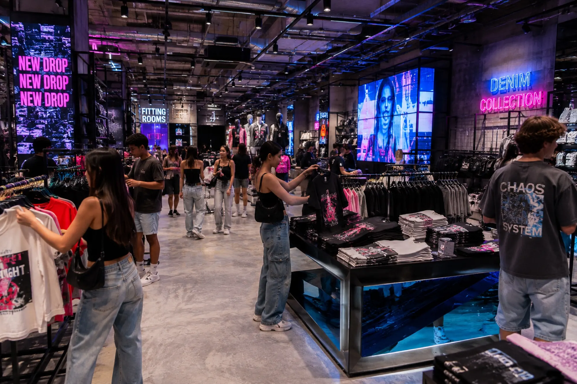 Compradores recorriendo un piso de ropa de moda con un vendedor en el mostrador